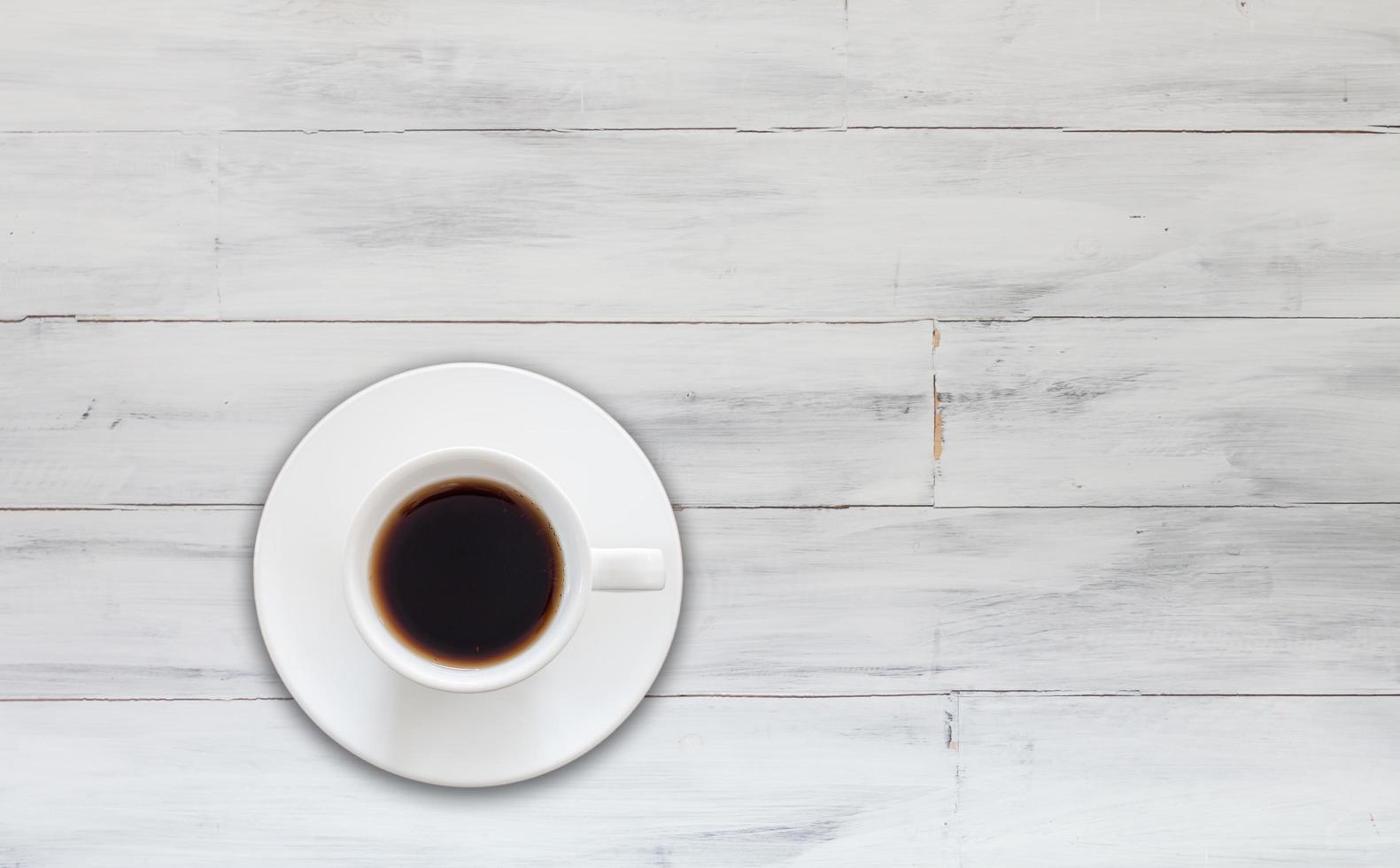 vista dall'alto della tazza di caffè su fondo di legno bianco foto