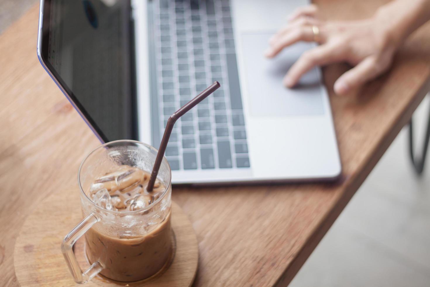 caffè freddo con persona che lavora su un computer portatile foto