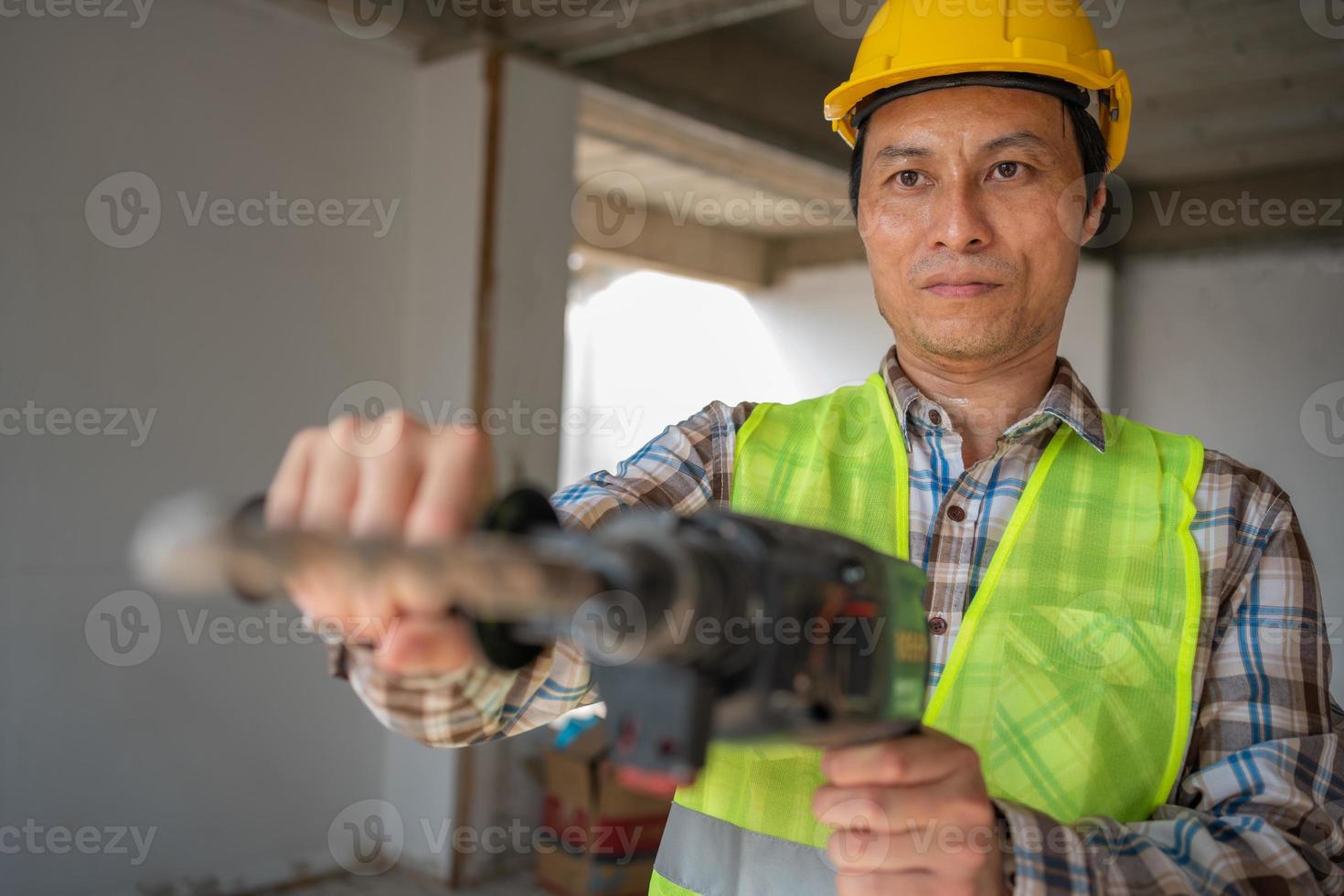 costruzione lavoratore utilizzando un elettrico martello pneumatico per trapano perforatore attrezzatura fabbricazione fori prima scrosciante il pavimento per essere forte a costruzione luogo, concetto di lavoratore e Residenziale costruzione. foto