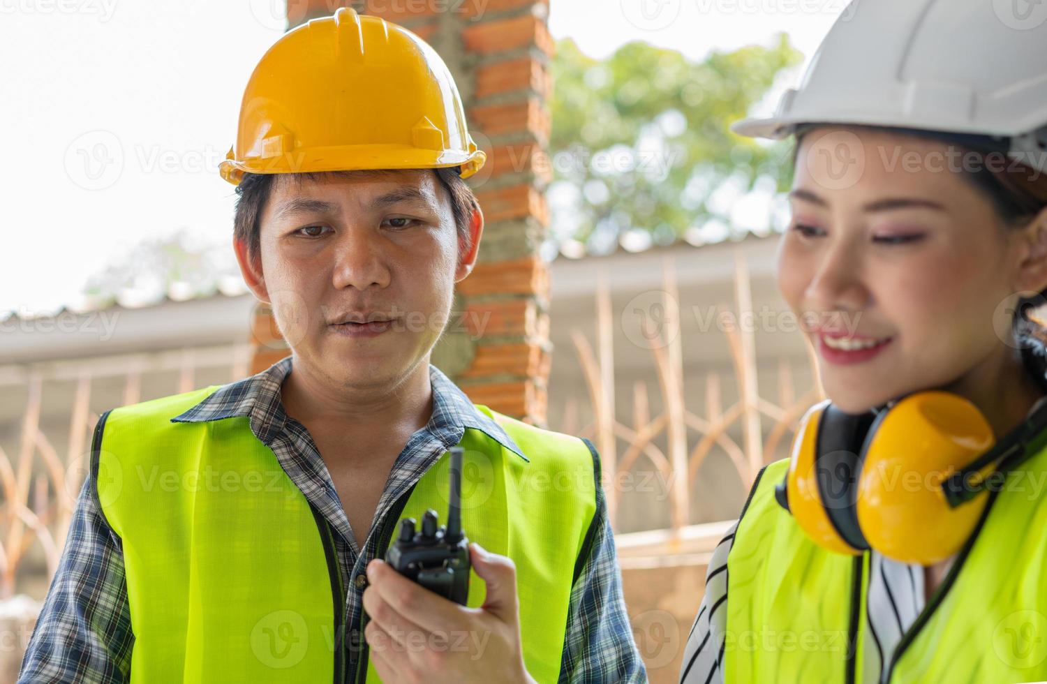 ingegnere asiatico o giovane architetto donna indossa un casco per la sicurezza e parla con un appaltatore su un progetto di fabbrica edile, concetto di lavoro di squadra, concetto di leadership. foto