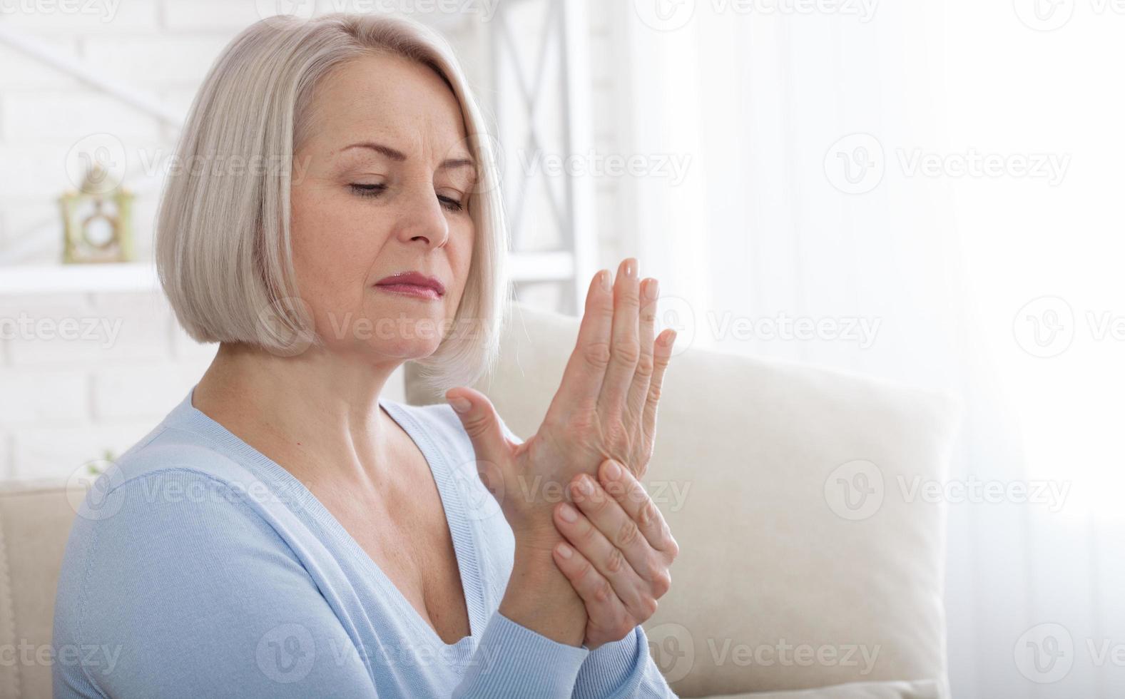 donna massaggio sua artritico mano e polso foto