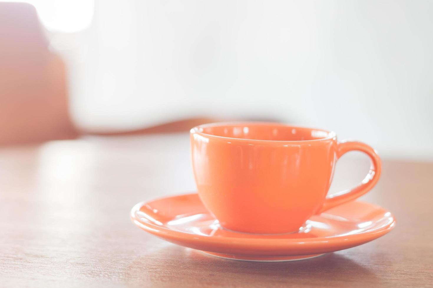 mini tazza di caffè arancione su un tavolo di legno foto