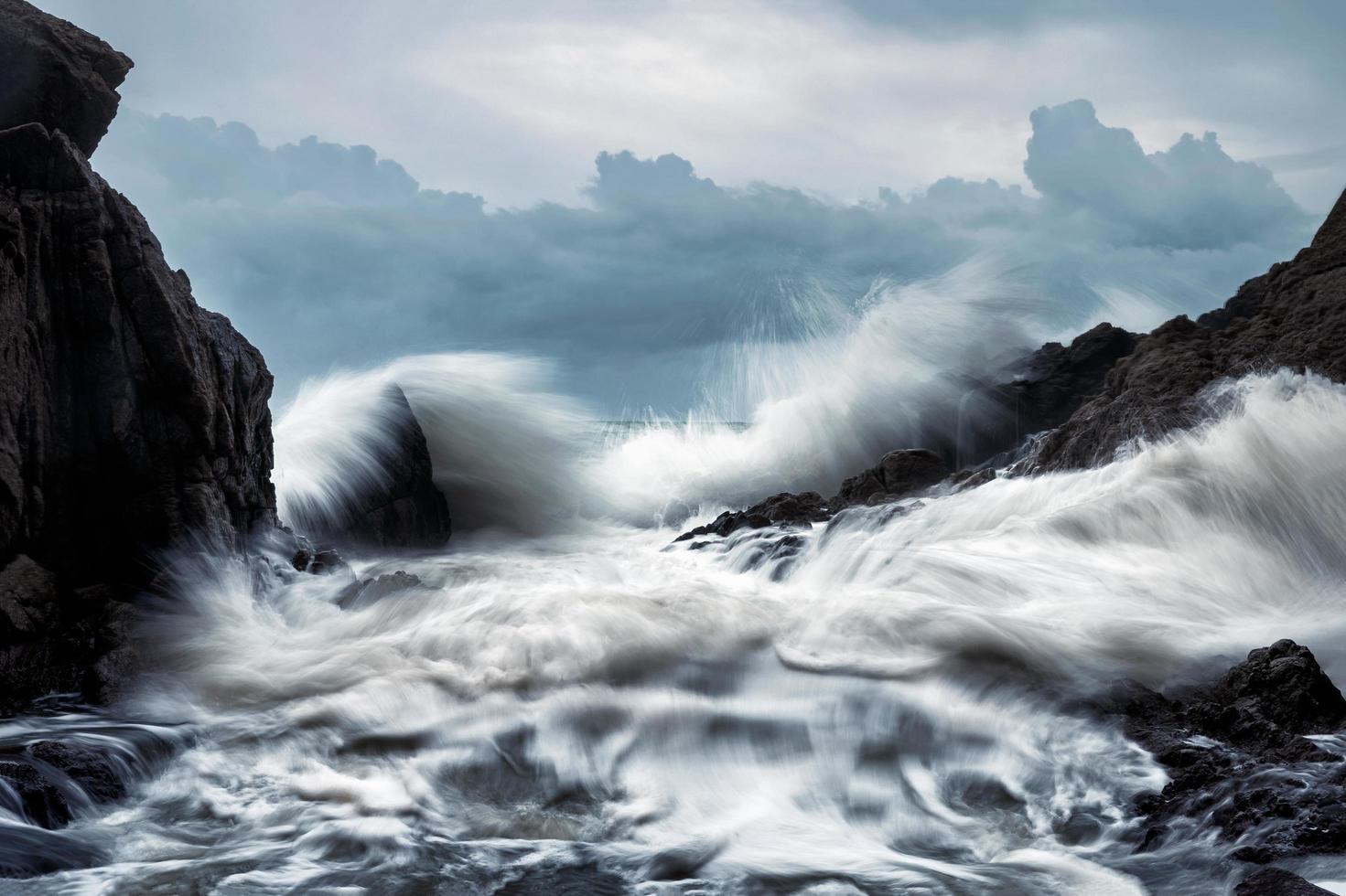 grande onda che colpisce le rocce in tempesta foto