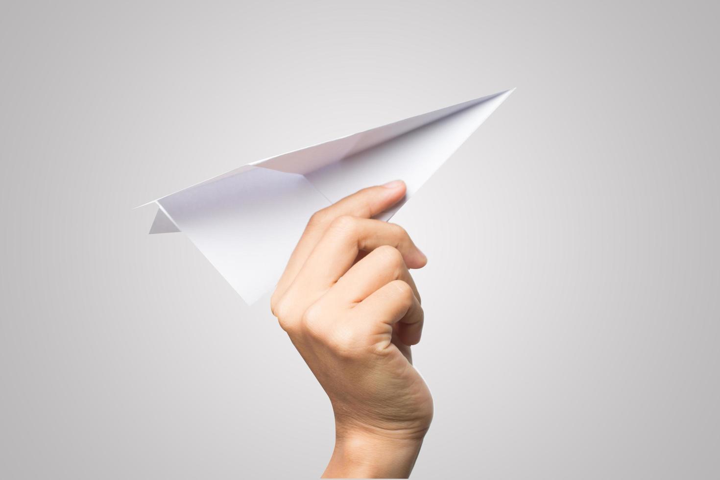 la mano di una donna tiene un aeroplano di carta su sfondo bianco foto