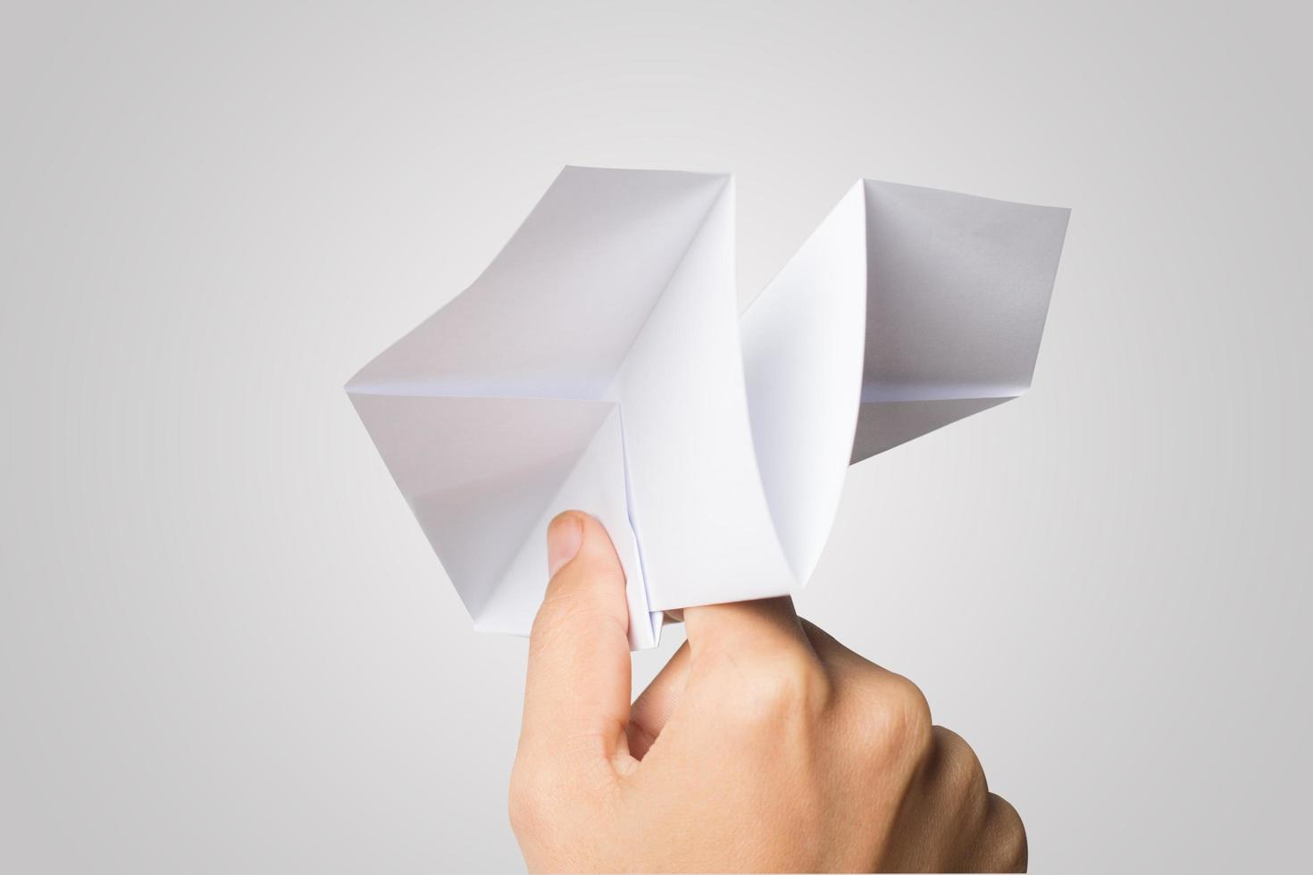 la mano di una donna tiene un aeroplano di carta su sfondo bianco foto