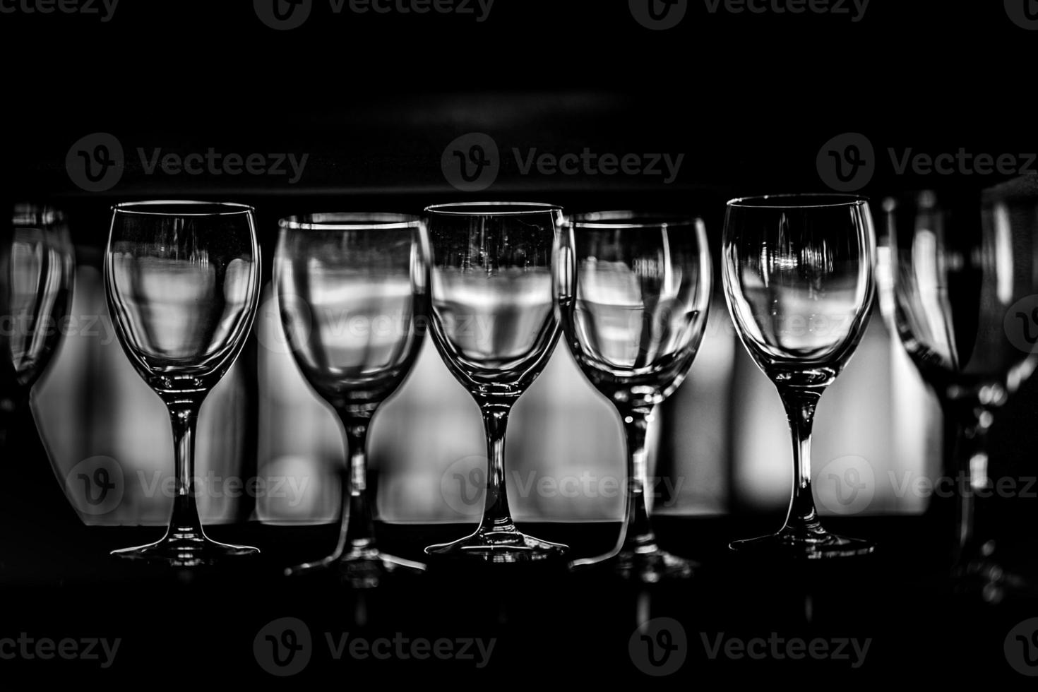 righe di vuoto vino bicchieri su il vetrina, nero e bianca fotografia foto