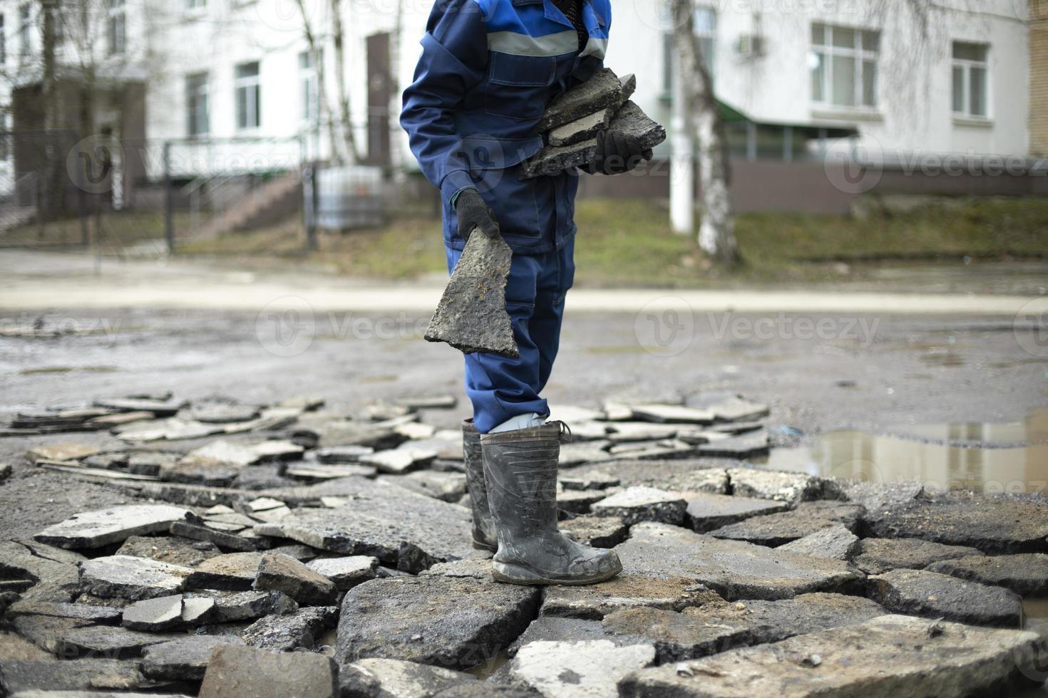 lavoratore lanci rocce a strada. cattivo strada riparazioni. costruttore sceglie costruzione detriti. foto