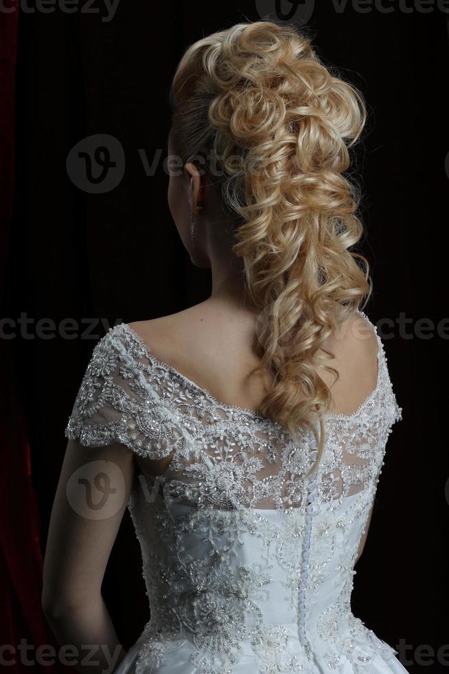 bionda bellezza acconciatura dietro a su un' buio sfondo bella.la lungo capelli di il sposa è ordinatamente in stile. foto