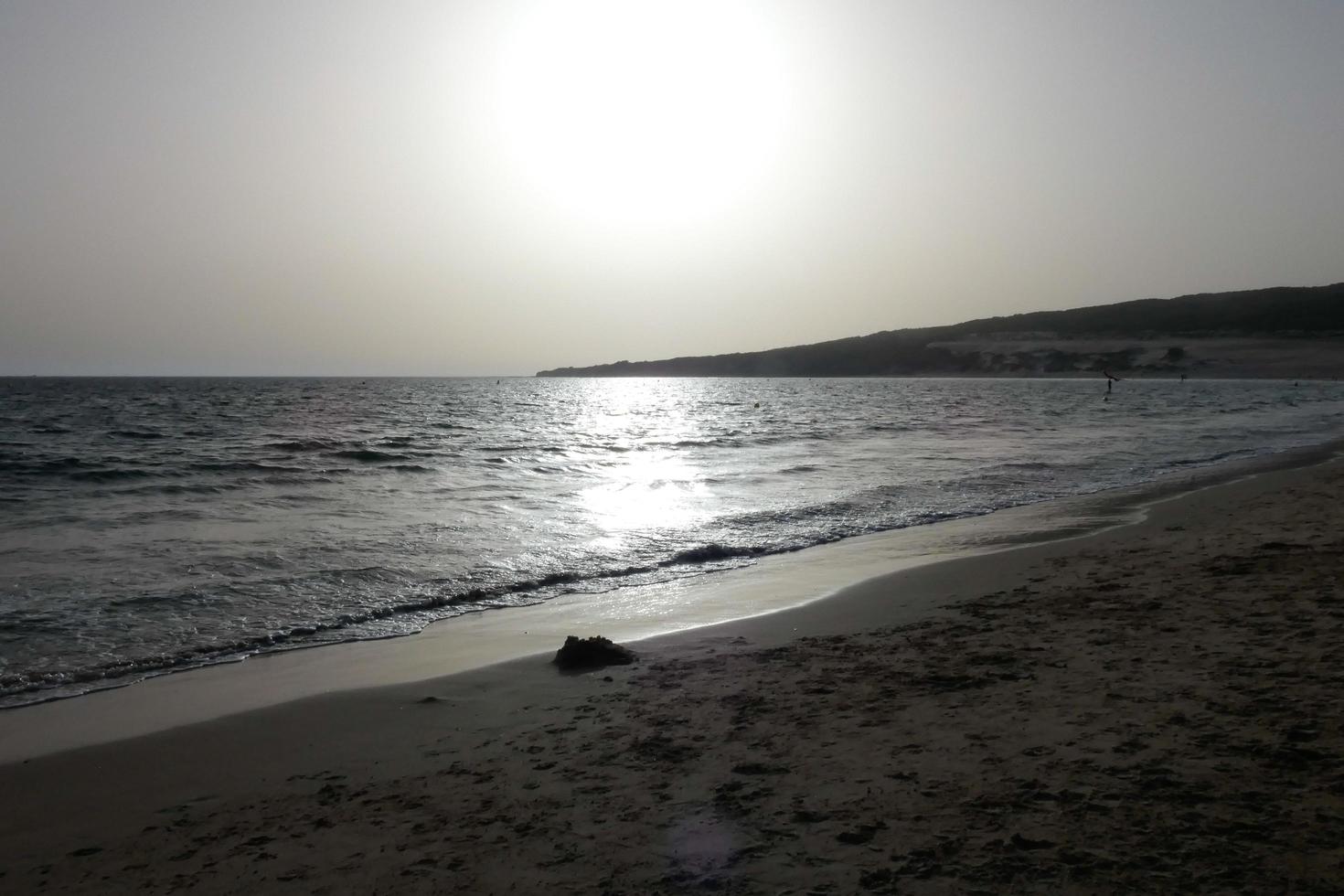 sole ambientazione al di sopra di il mare, tramonto nel autunno su il spiaggia di zahara de los intona, Cadice, andalusia, Spagna foto