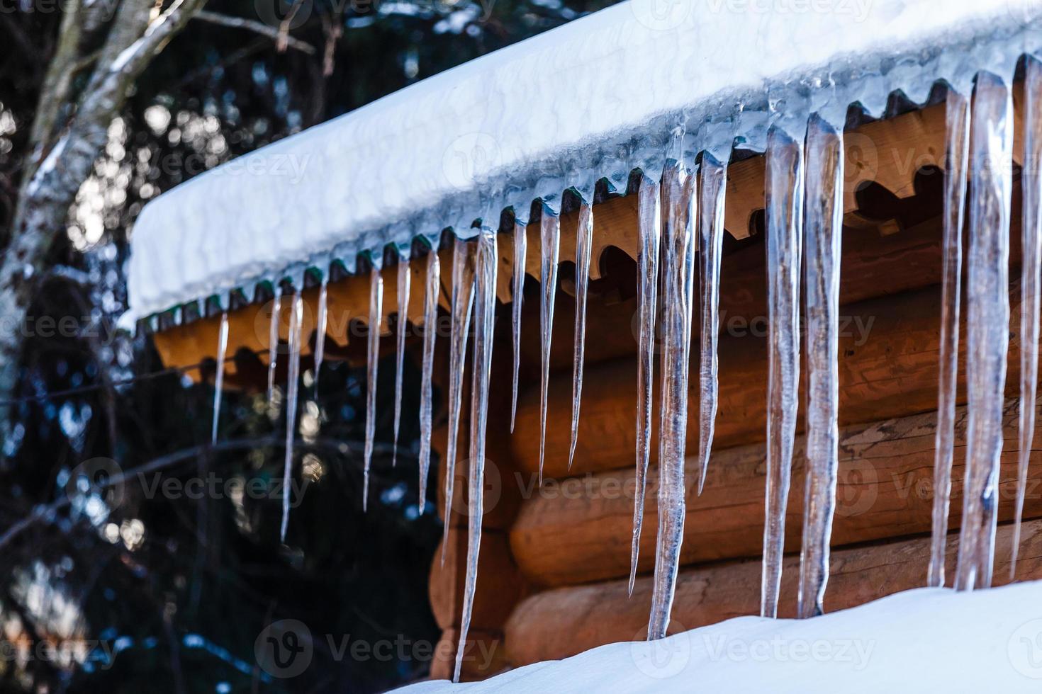 ghiaccioli sospeso a partire dal il di legno tetto, creativo inverno sfondo foto