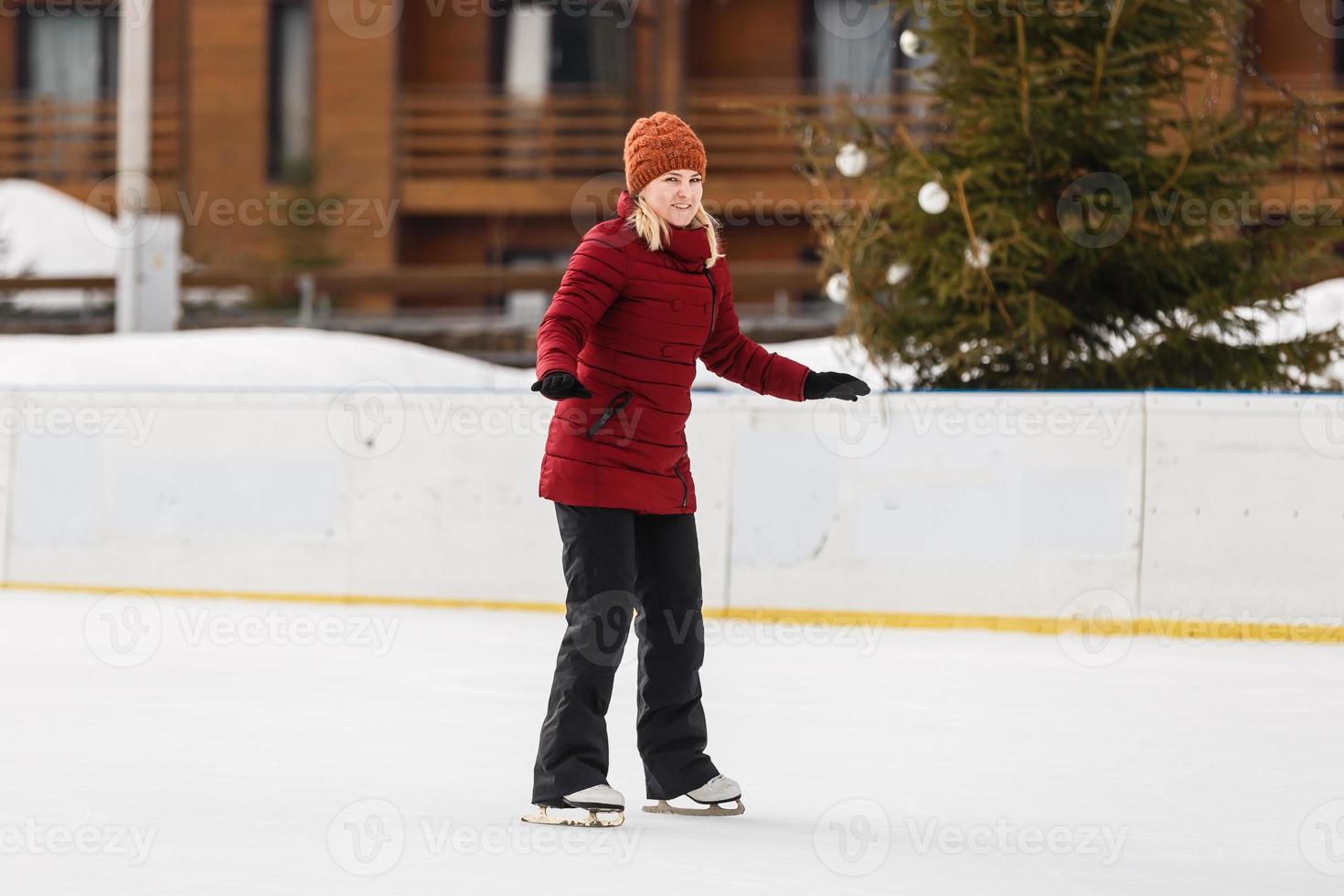attraente giovane donna avendo divertimento mentre pattinando a ghiaccio pista di pattinaggio, orario invernale foto