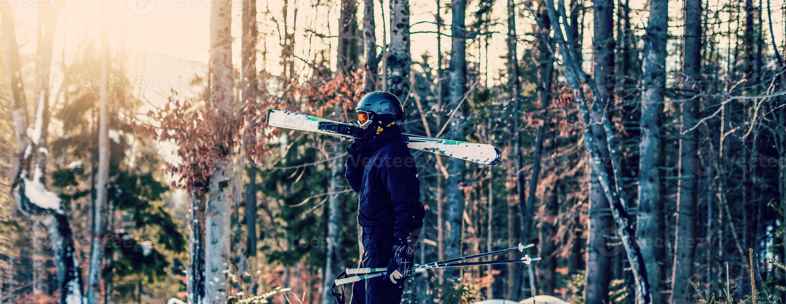 sciatore Tenere sciare e guardare a bellissimo neve coperto montagne. giovane uomo pensiero e guardare nevoso montagna con copia spazio. lato Visualizza di inverno sciatore tipo con maschera Tenere sciare attrezzatura all'aperto. foto