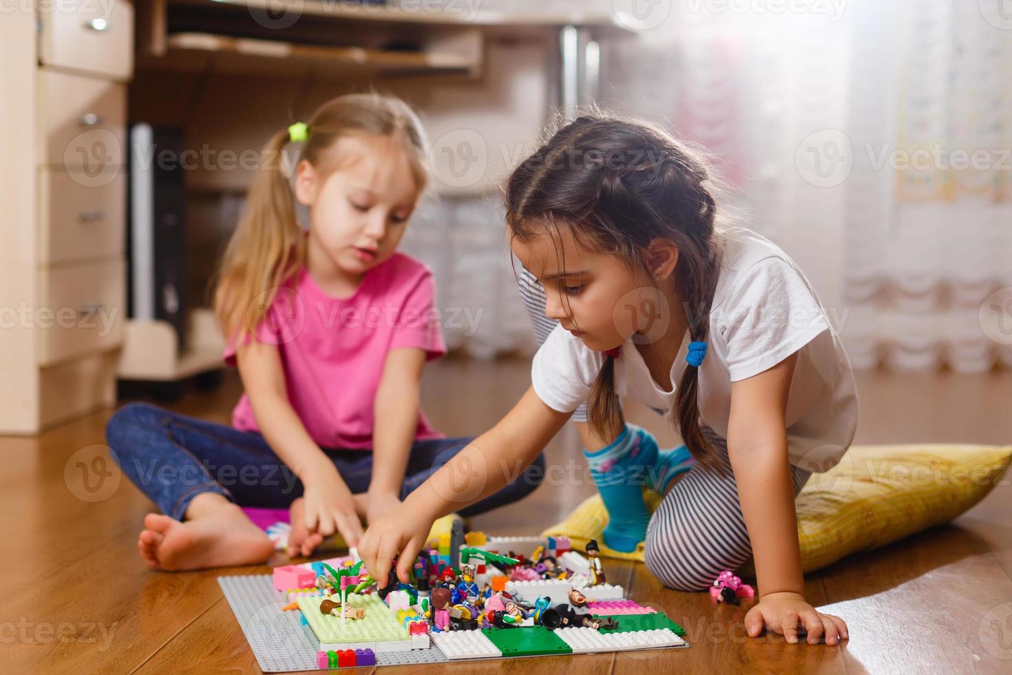 Due carino poco bambini siamo giocando con blocchi contento ragazze a casa divertente bello sorelle foto