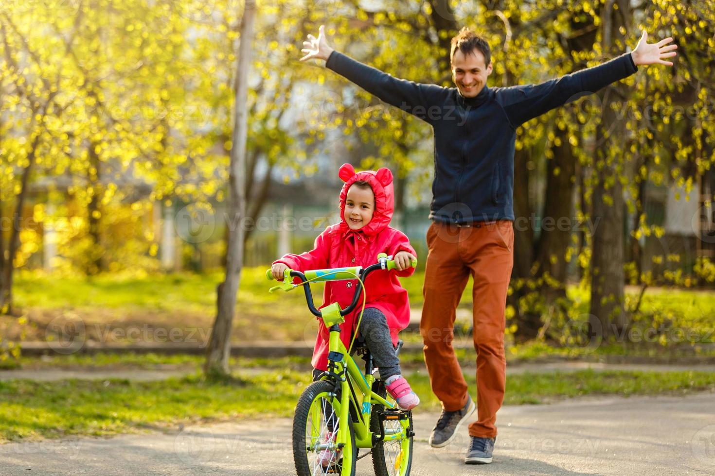 contento padre gioisce quello sua figlia imparato per cavalcata un' bicicletta foto