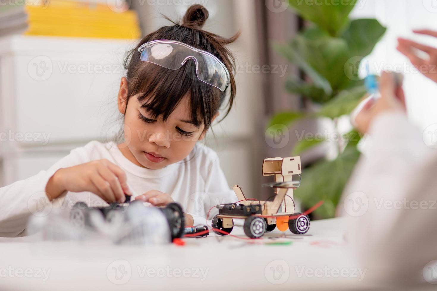 gli studenti asiatici imparano a casa a codificare auto robot e cavi di schede elettroniche in stelo, vapore, matematica ingegneria scienza tecnologia codice informatico in robotica per bambini concetto. foto