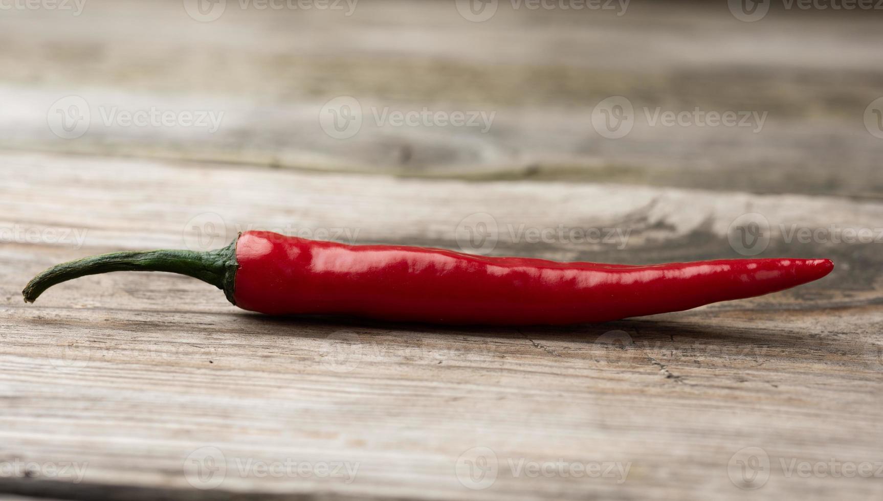 baccello di rosso chili Pepe su un' grigio di legno tavola foto