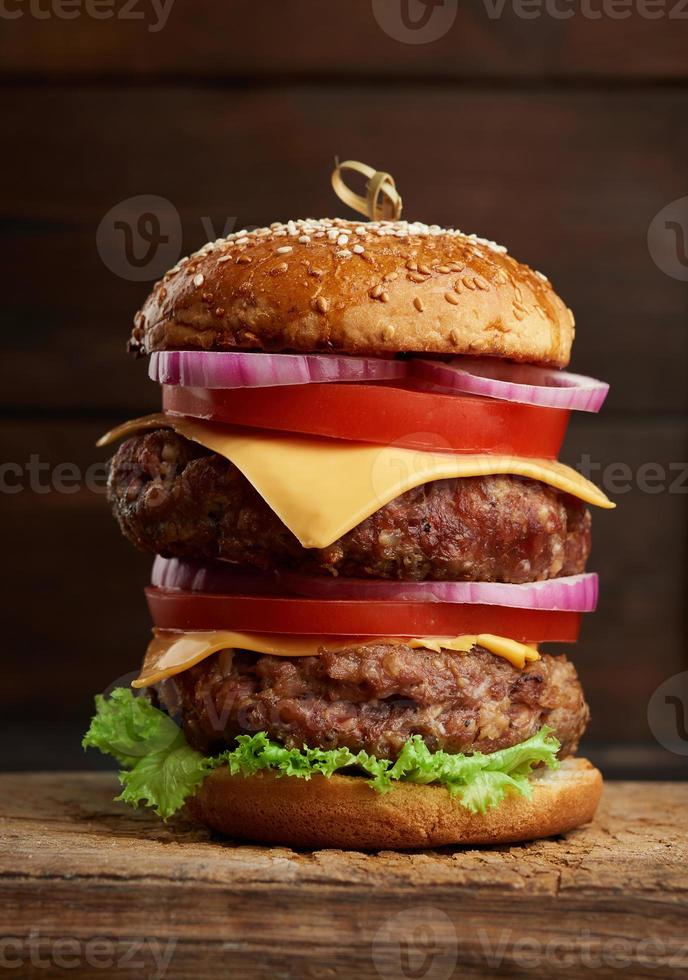 Doppio hamburger al formaggio con pomodori, cipolle, barbecue cotoletta e sesamo ciambella foto