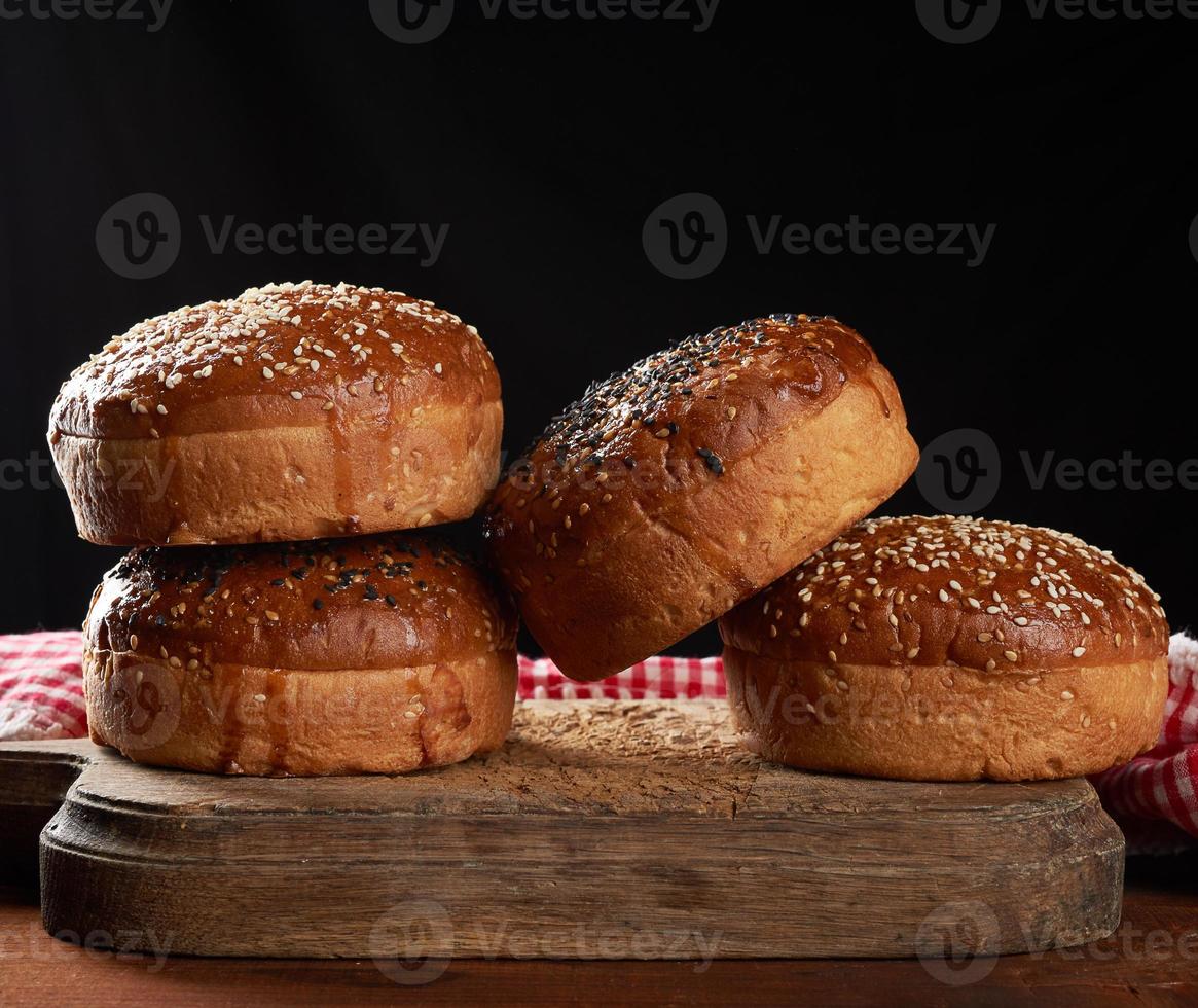 al forno il giro croccante sesamo panini per hamburger su Marrone di legno tavola foto