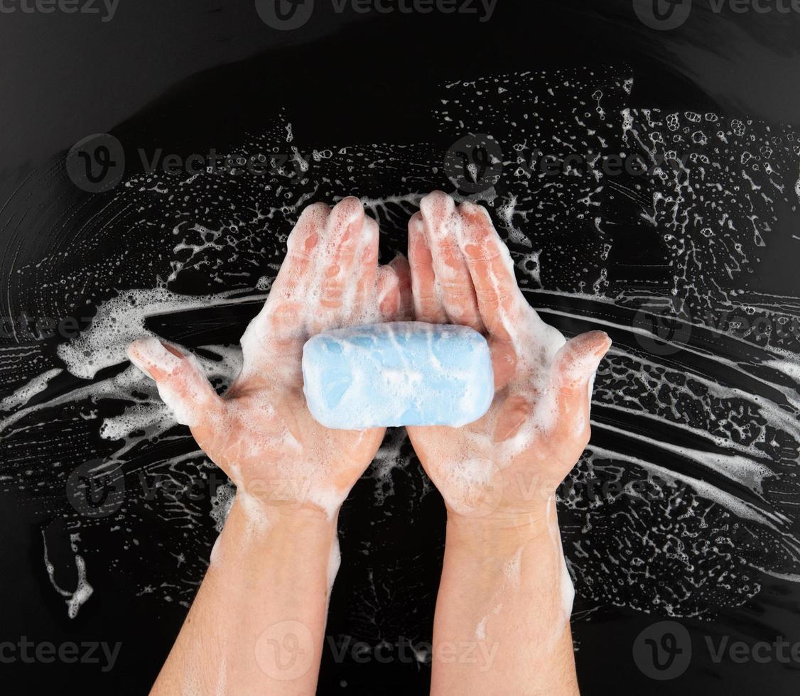 processi di lavaggio mani con blu sapone, parti di il corpo nel bianca schiuma su un' nero sfondo foto
