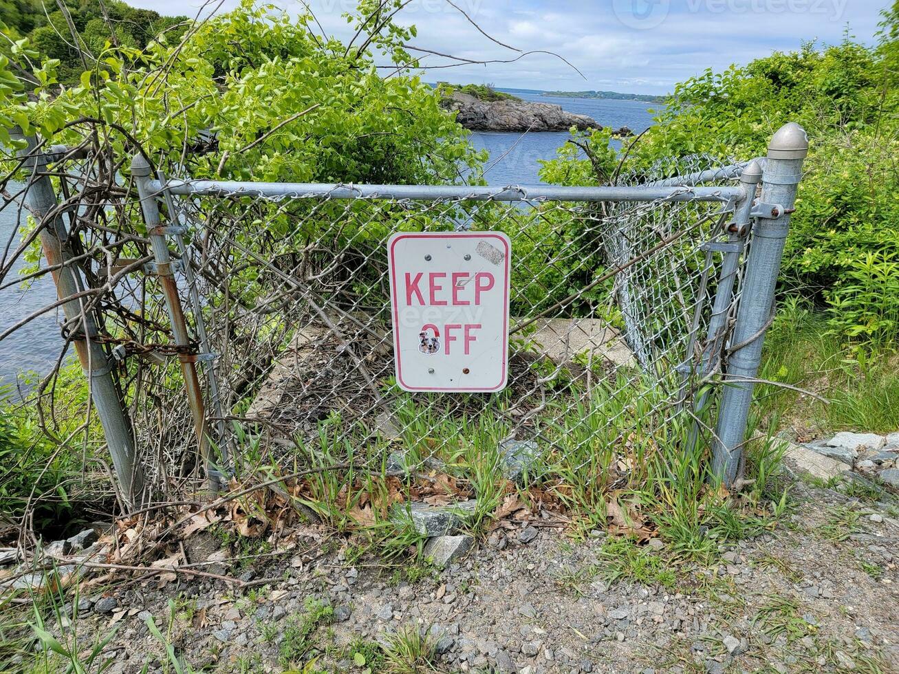 mantenere via cartello su metallo recinto vicino acqua vicino mare foto