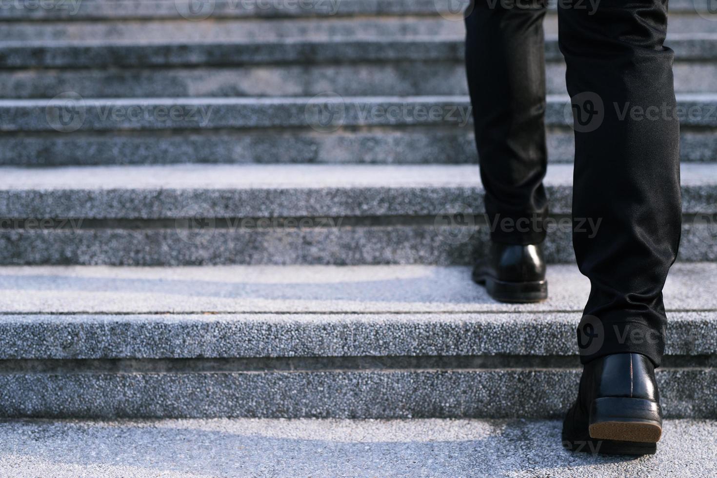 moderno uomo d'affari Lavorando avvicinamento gambe a piedi su il le scale nel moderno città. nel corsa ora per opera nel ufficio un' fretta foto