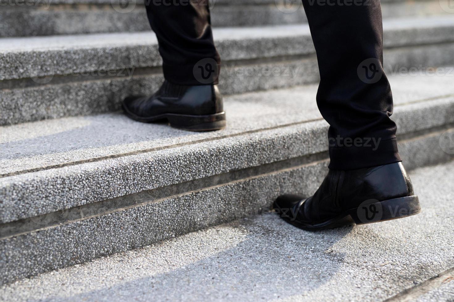 moderno uomo d'affari Lavorando avvicinamento gambe a piedi su il le scale nel moderno città. nel corsa ora per opera foto