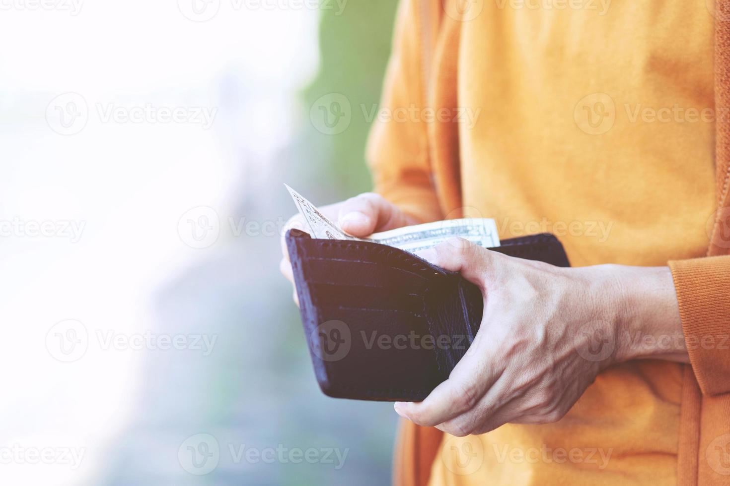 uomo è Tenere un' portafoglio con i soldi foto