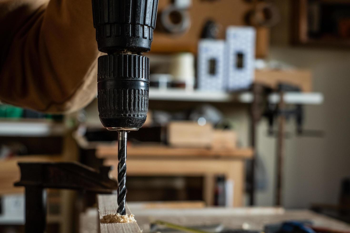 carpentiere che fa un trapano con una trottola su una tavola di legno foto