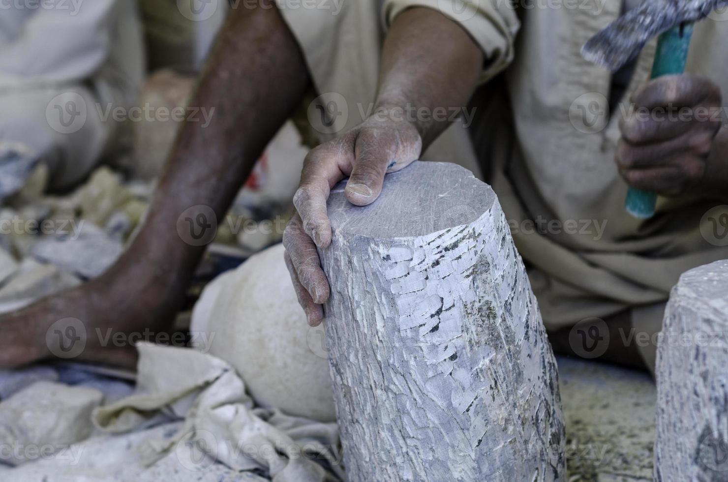 mani di uno scultore egiziano maschio mentre lavora con una pietra alabastro foto