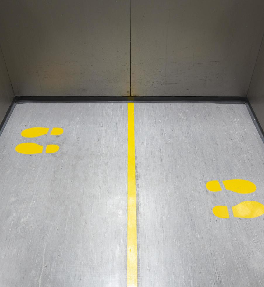 sociale distanziamento per covid-19 con giallo orma cartello nel pubblico ascensore foto
