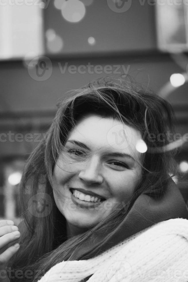 vicino su donna sorridente su strada con luci monocromatico ritratto immagine foto