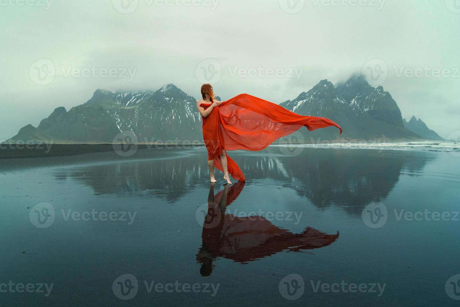 attraente modello con agitando tessuto su reynisfjara spiaggia panoramico fotografia foto