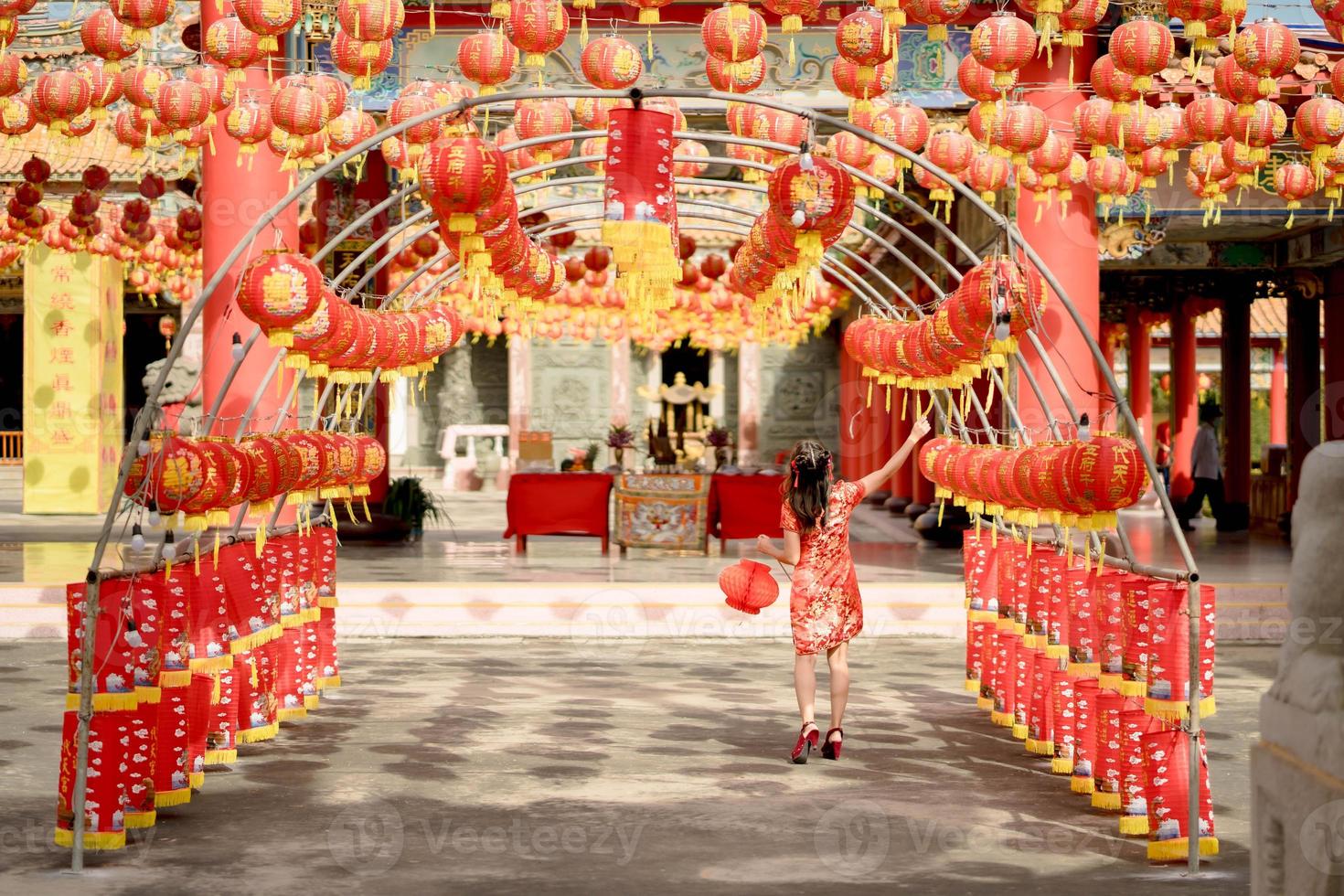bellissimo giovane asiatico donna indossare tradizionale cheongsam qipao vestito Tenere lanterna e a piedi con sua indietro mentre visitare il Cinese buddista tempio. celebrare Cinese lunare nuovo anno. foto