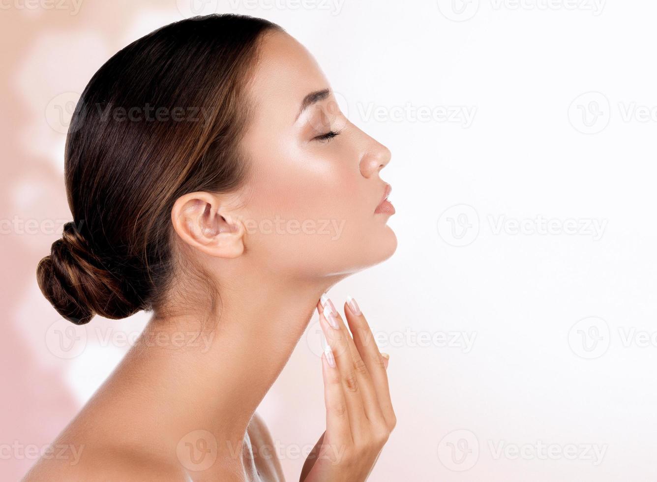bella donna tocchi sua collo contro un astratto sfondo con sfocato luci foto