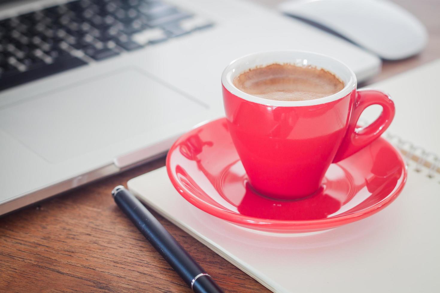 primo piano di una tazza rossa e di un laptop foto