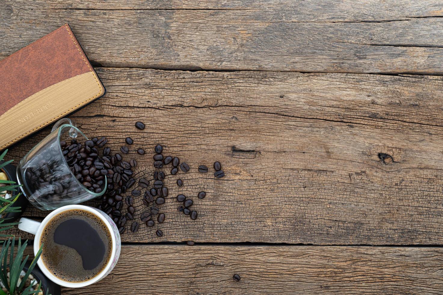 scrivania in legno con chicchi di caffè e notebook foto