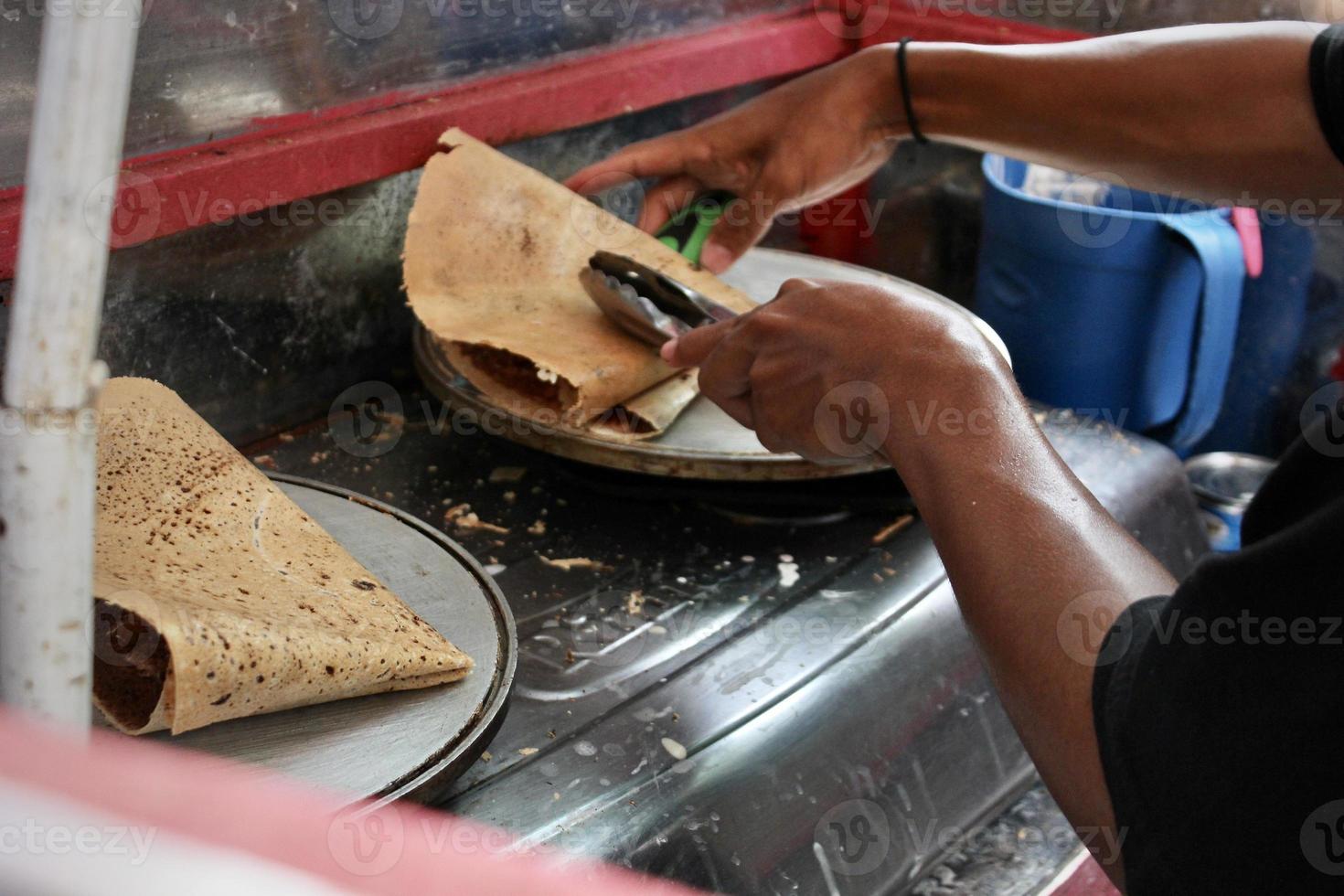 un' giovane venditore è fabbricazione merenda crepes su un' strada vicino un' tema parco foto