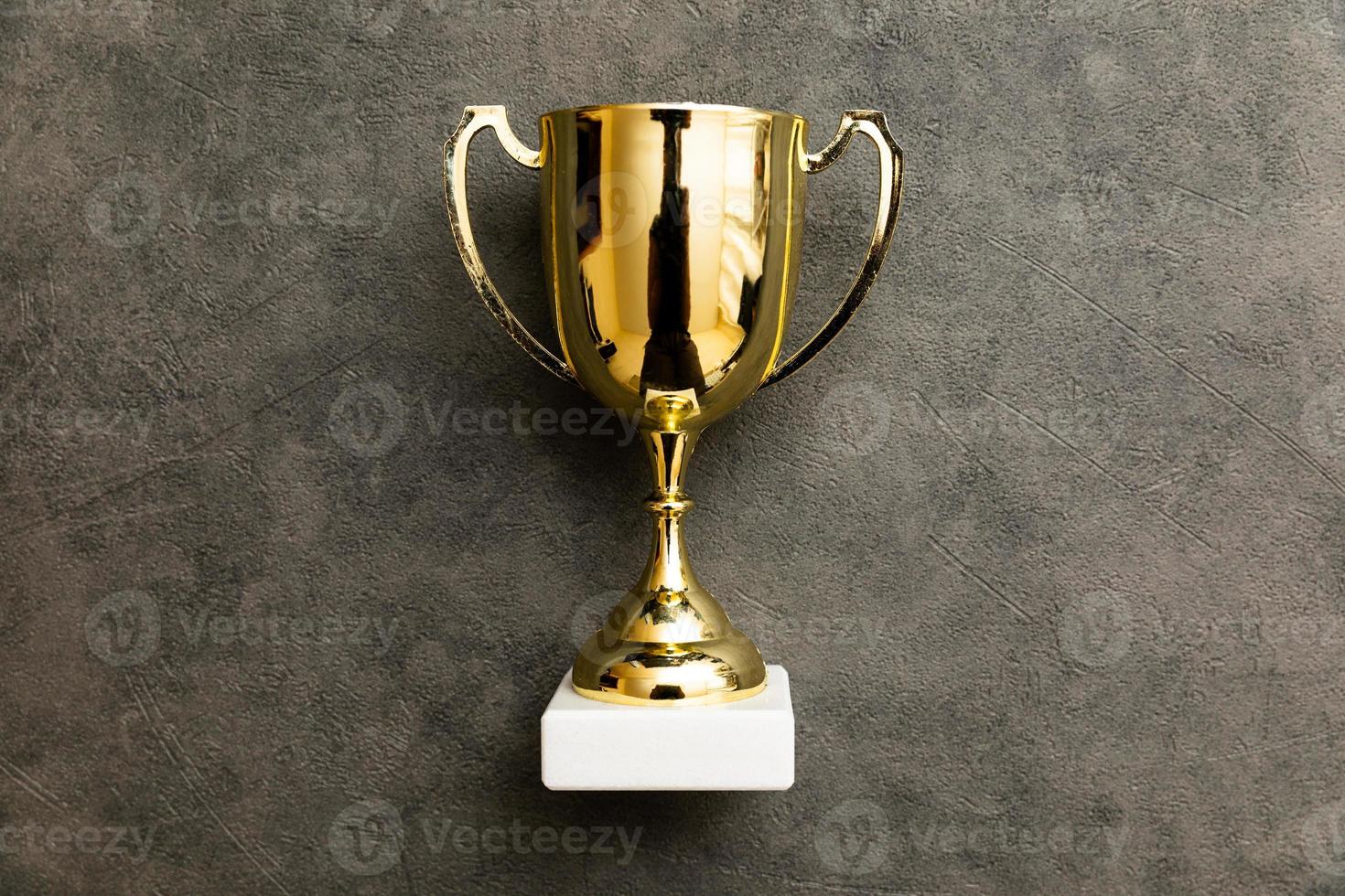 semplicemente piatto posare design vincitore o campione oro trofeo tazza su calcestruzzo pietra grigio sfondo. vittoria primo posto di concorrenza. vincente o successo concetto. superiore Visualizza copia spazio. foto