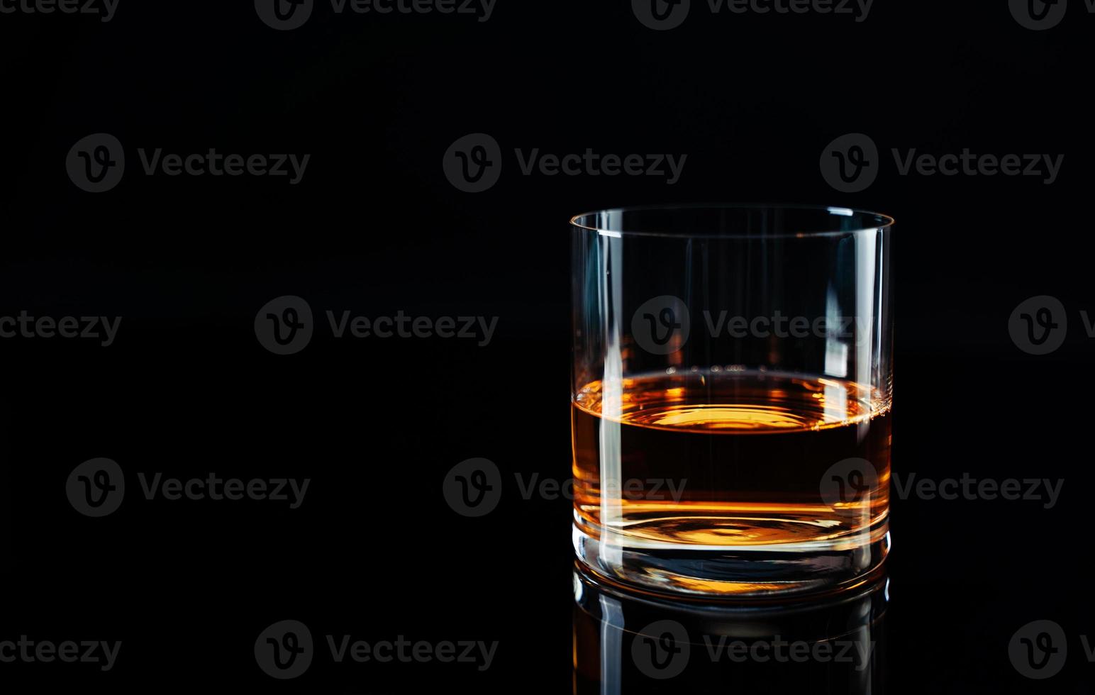elegante semplice bicchiere di lusso Whisky contro nero sfondo. brillante whisky bicchiere isolato sfondo, studio sparo. copyspace. forte alcool bevanda. foto