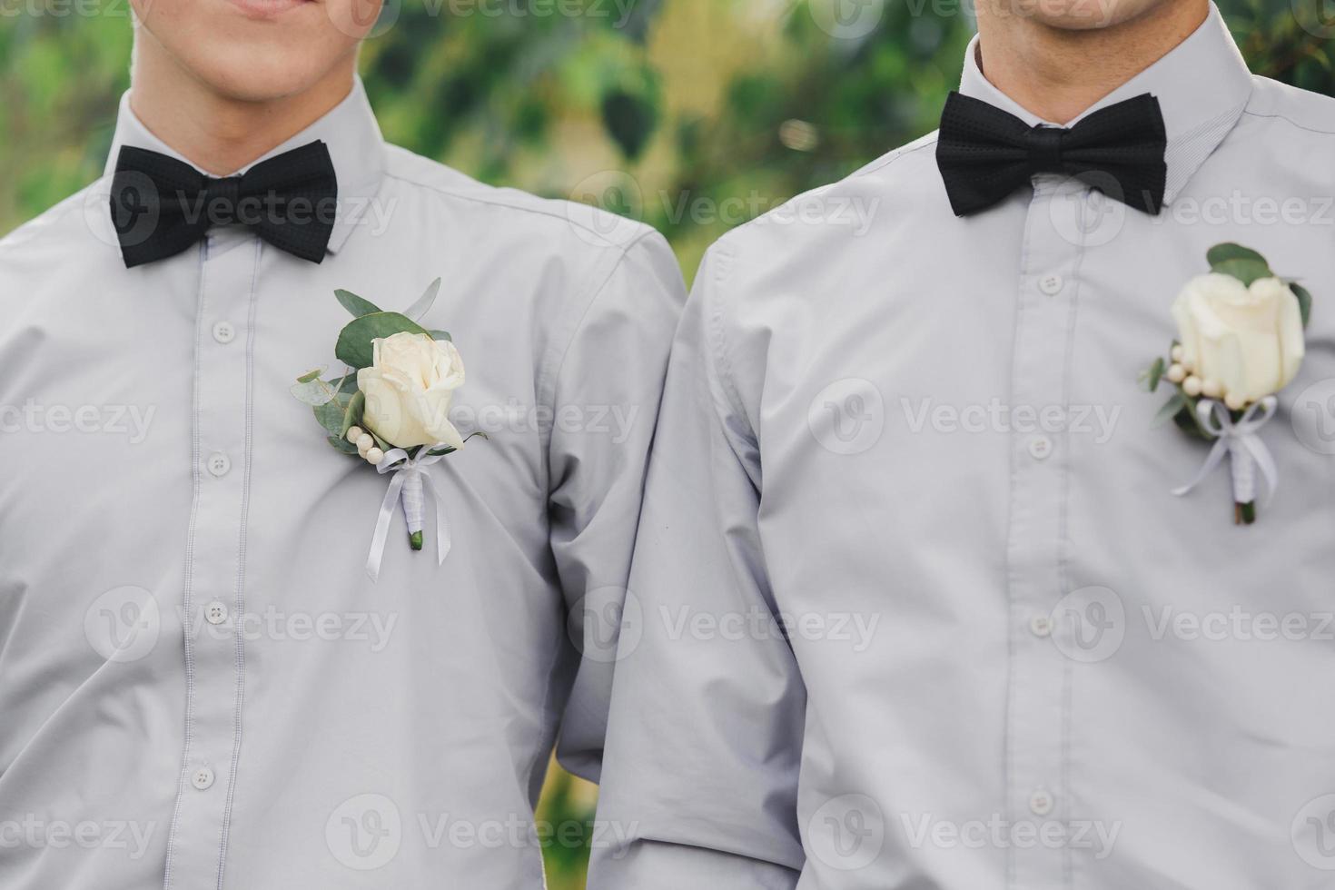 bianca Rose fiori nel asola, Due sposi amici è vestito nel un' grigio camicia e un' arco legare. nozze giorno. attrezzatura di il giorno. foto