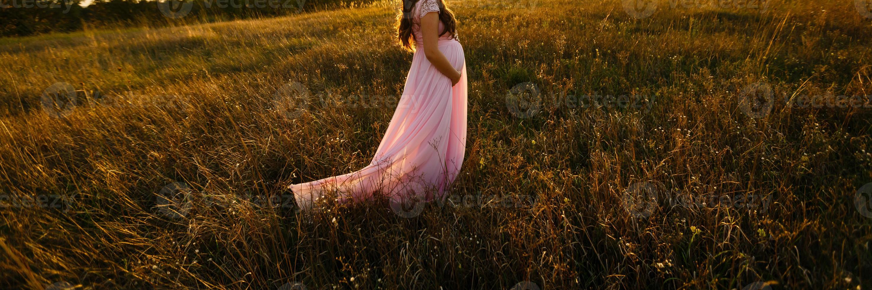 vicino su di incinta donna a tramonto foto