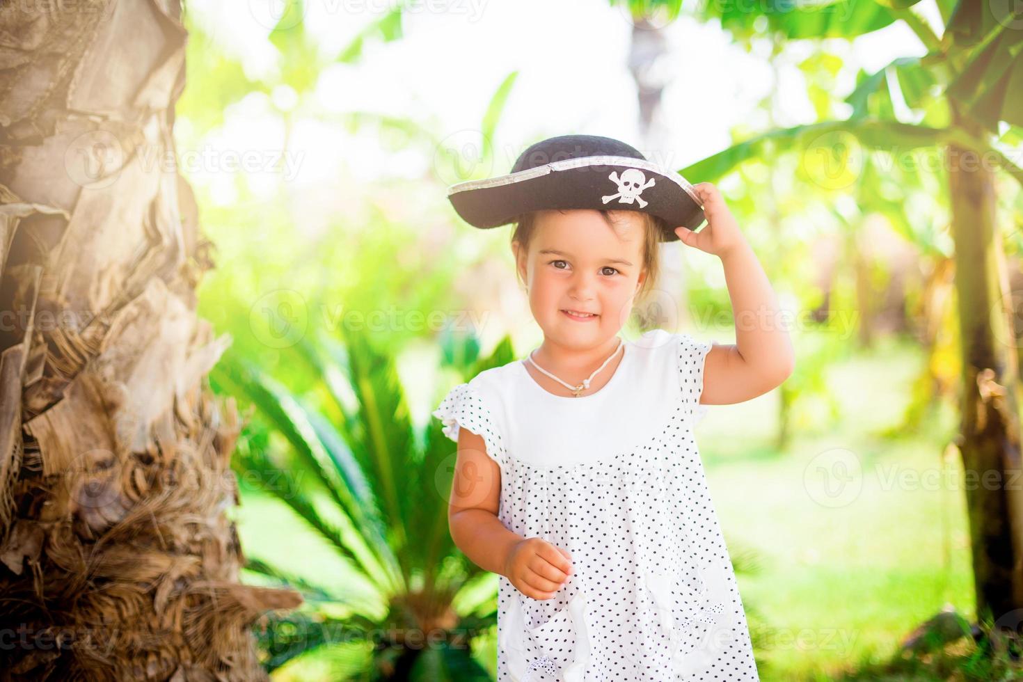 bellissimo poco ragazza nel pirata cappello con un' cranio Tenere un' stella marina su il spiaggia foto