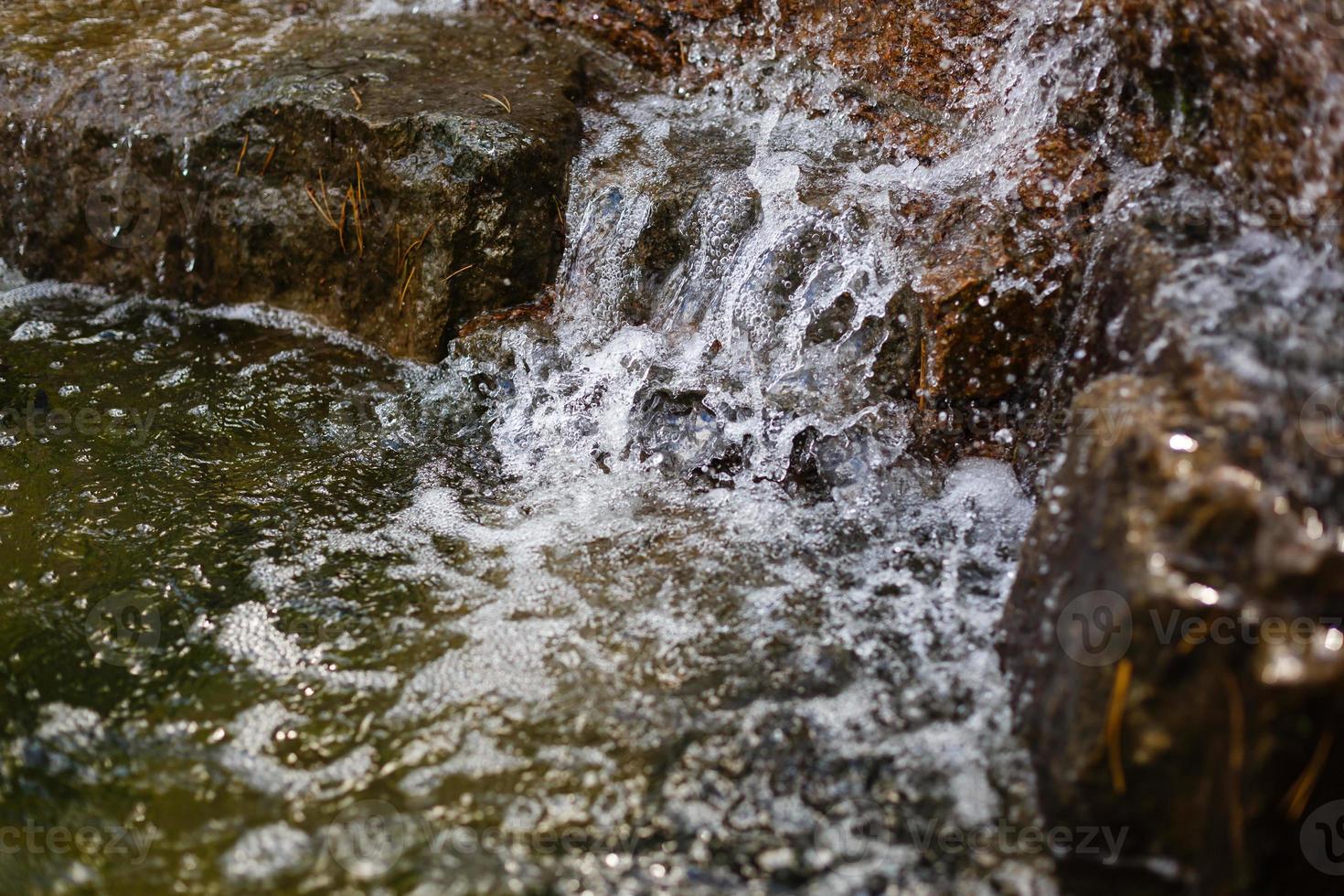 vicino su di acqua spruzzi su rocce a partire dal un' cascata foto