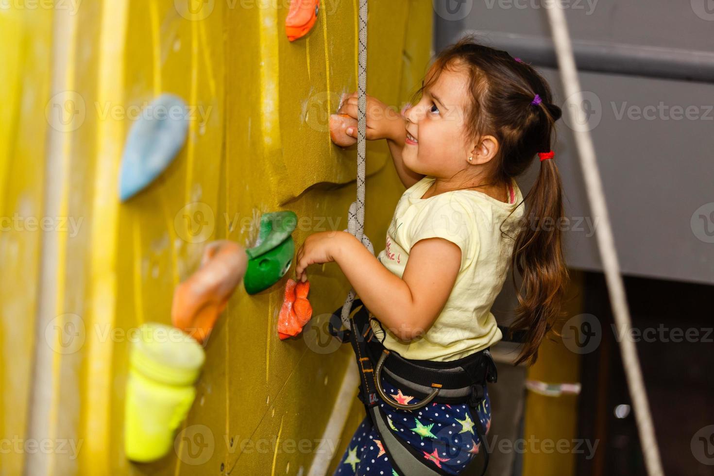 poco ragazza ascendente nel all'aperto roccia arrampicata Palestra foto