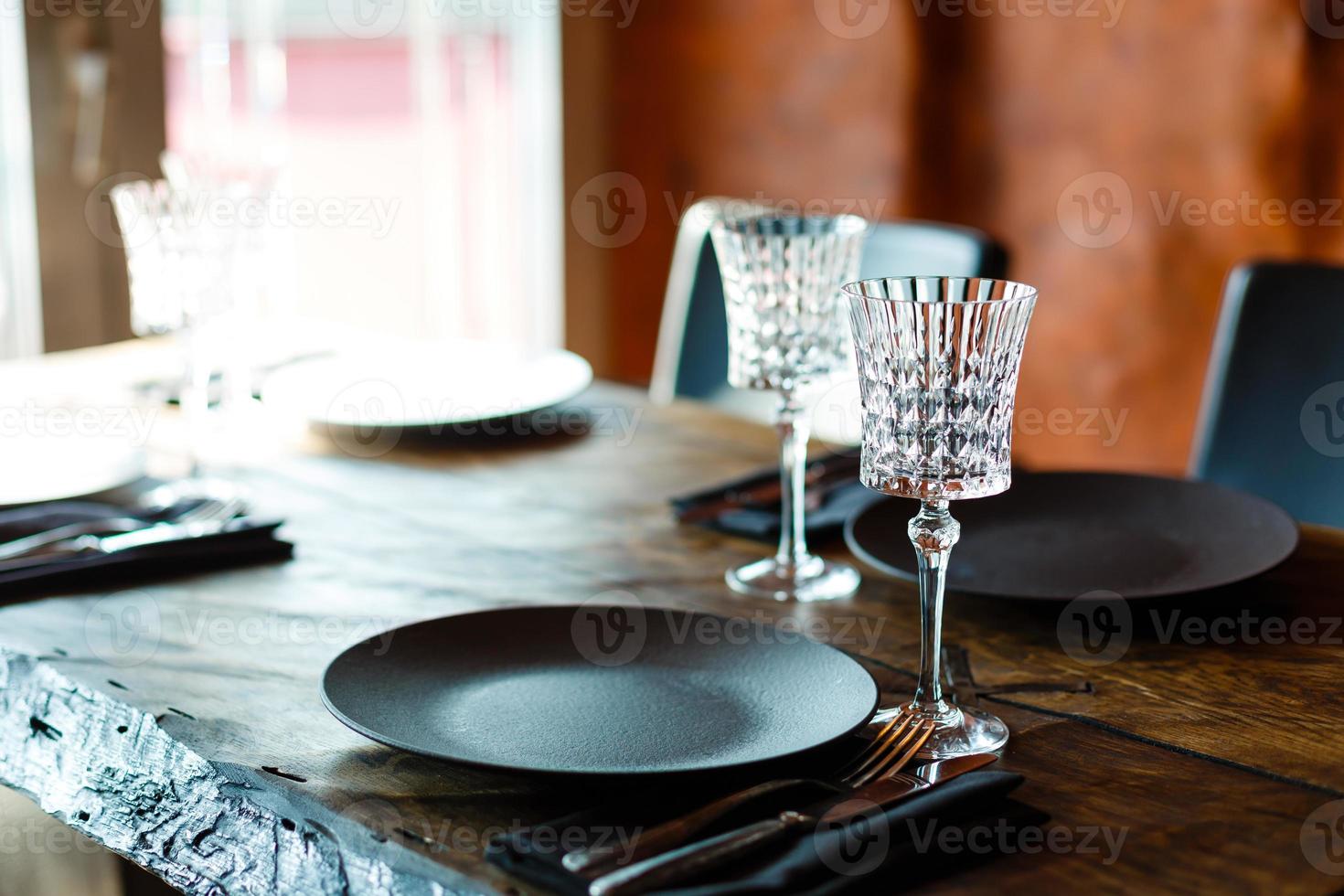 occhiali, forchette, coltelli, piatti su un' tavolo nel ristorante servito per cena foto