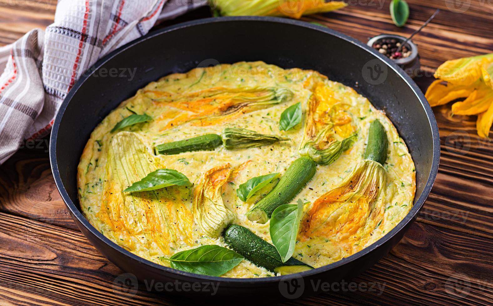 forno al forno frittata con fiori zucchine nel padella su di legno sfondo. foto