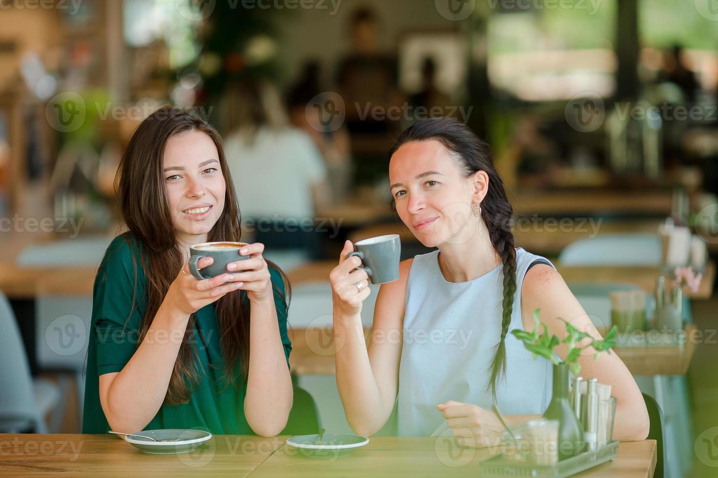 contento sorridente giovane donne con caffè tazze a bar. comunicazione e amicizia concetto foto