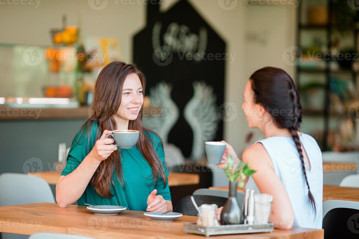 contento sorridente giovane donne con caffè tazze a bar. comunicazione e amicizia concetto foto