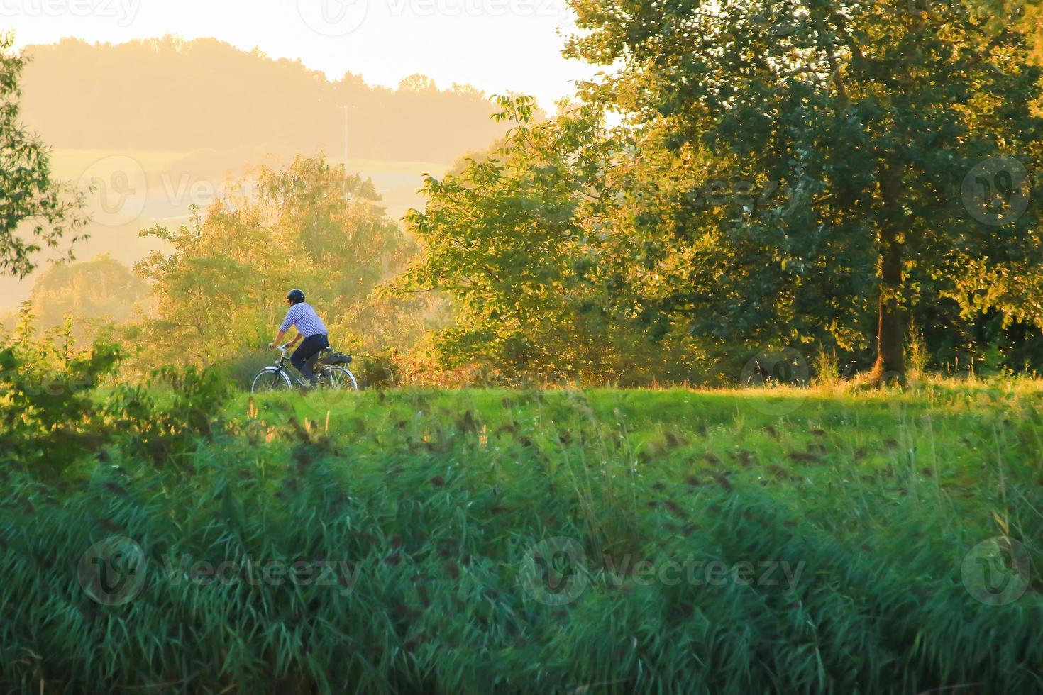 persone siamo equitazione il bicicletta su un' rurale strada a tramonto lungo danubro fiume nel Ratisbona, Germania, Europa. foto