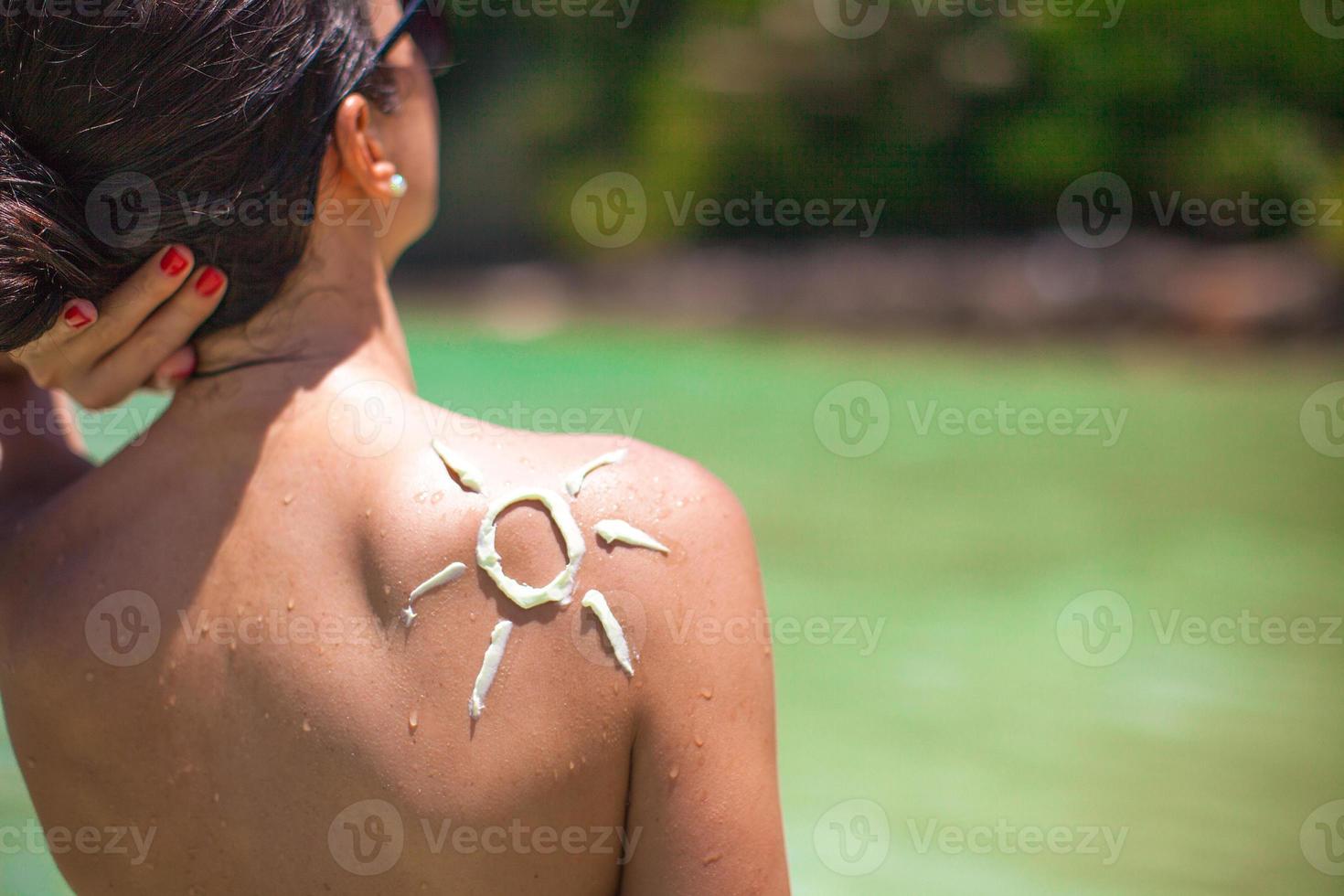 avvicinamento sole fatto con crema solare a il donna di spalla foto